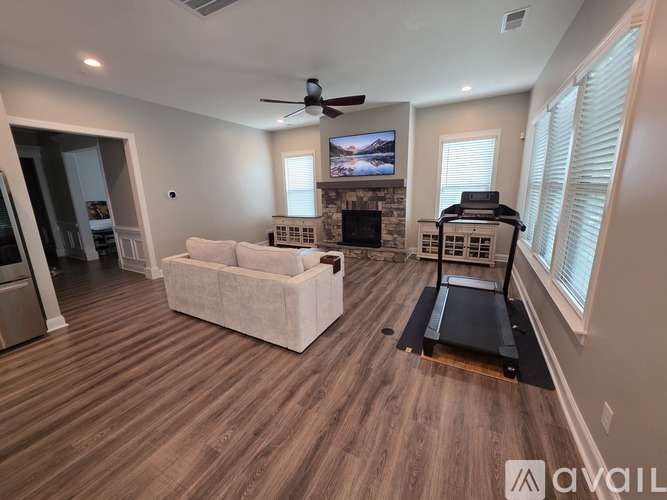 A living room with a couch, a treadmill, and a television.