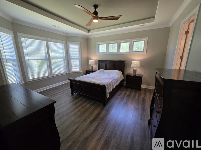 A bedroom with a bed, dresser, and ceiling fan.