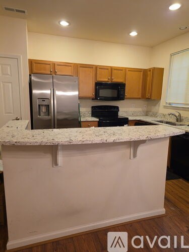 A kitchen with a granite counter top and wooden cabinets.