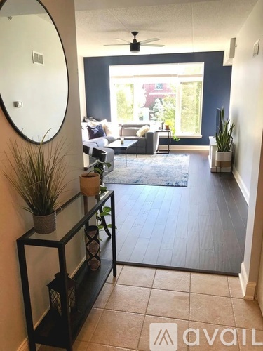 A living room with a round mirror on the wall and a glass shelf with plants on it.