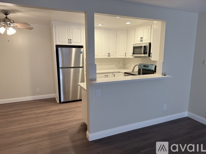 A kitchen with a stainless steel refrigerator and white cabinets.