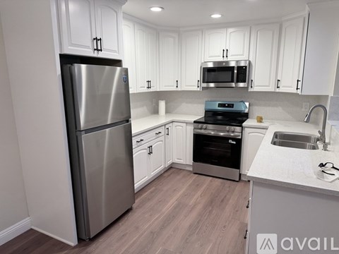 A kitchen with a stainless steel refrigerator and white cabinets.