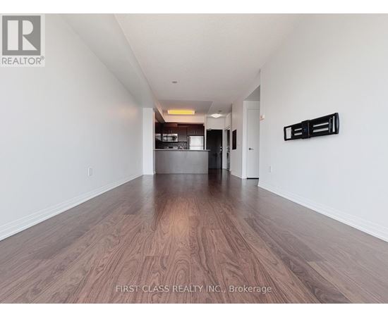 A long hallway with wood floors and white walls.