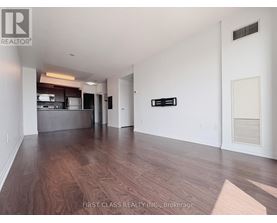 A spacious room with wooden flooring and white walls.