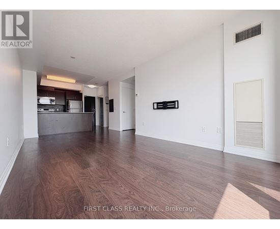 A spacious room with wooden flooring and white walls.