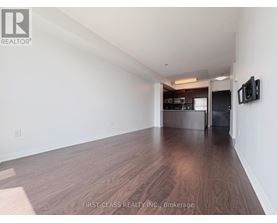 A room with wooden flooring and a television mounted on the wall.