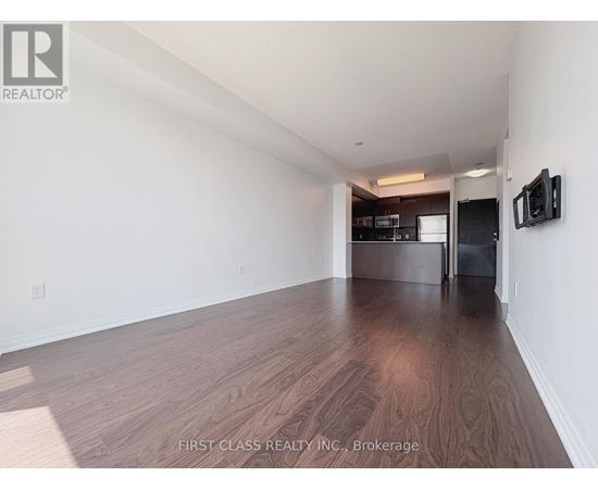 A room with wooden flooring and a television mounted on the wall.