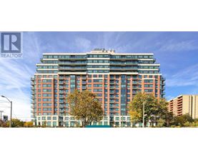 A tall building with many windows is surrounded by trees.