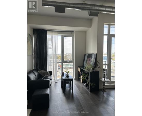 A living room with a black couch and a framed picture of a woman's face on the wall.