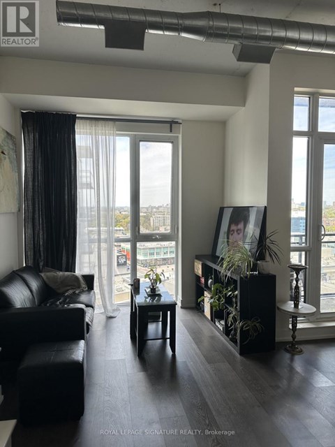 A living room with a black couch and a framed picture of a woman's face on the wall.