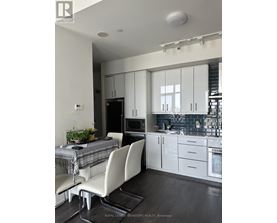 A modern kitchen with white cabinets and a dining table with a plaid tablecloth.