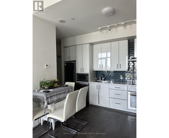 A modern kitchen with white cabinets and a dining table with a plaid tablecloth.