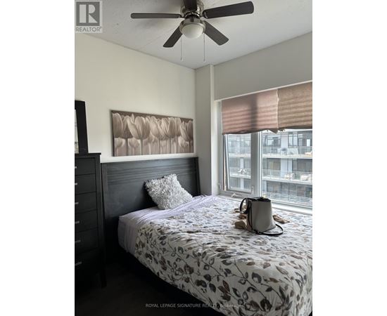 A bedroom with a bed, a ceiling fan, and a window with blinds.