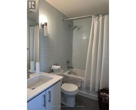 A white bathroom with a toilet, sink, and shower.