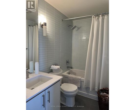A white bathroom with a toilet, sink, and shower.