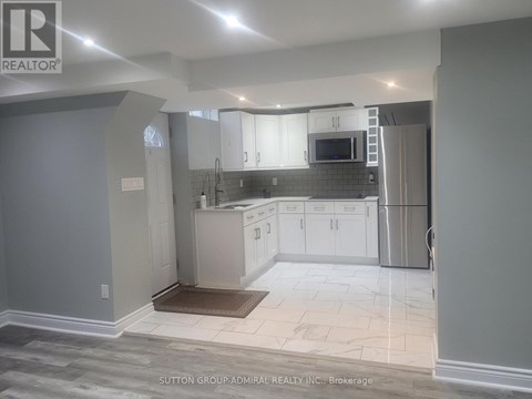 A kitchen with white cabinets and a refrigerator.