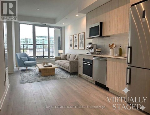 A modern kitchen and living room with a blue chair and a coffee table.