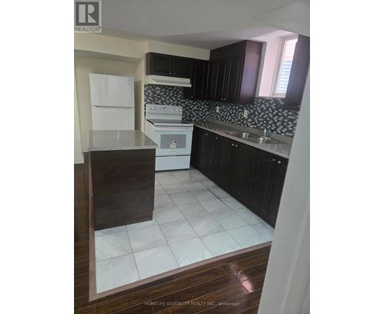 A kitchen with black cabinets and a white fridge.