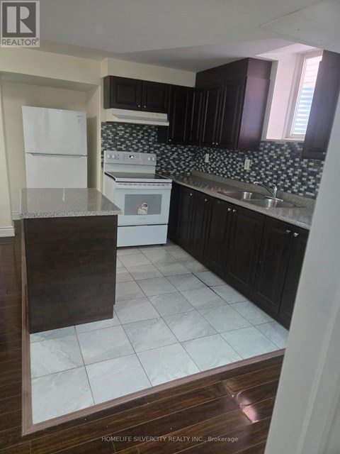 A kitchen with black cabinets and a white fridge.