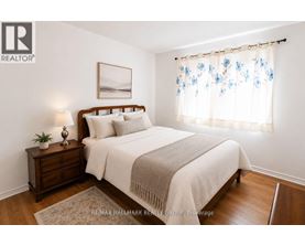 A bedroom with a bed, nightstand, and window with curtains.