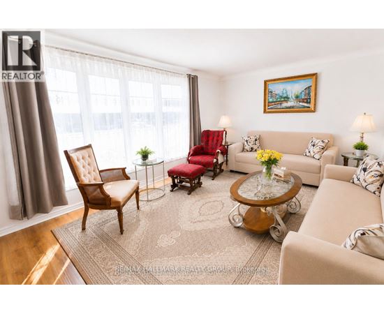 A living room with a brown chair, a red chair, a beige couch, and a painting on the wall.