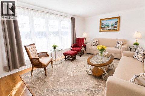 A living room with a brown chair, a red chair, a beige couch, and a painting on the wall.