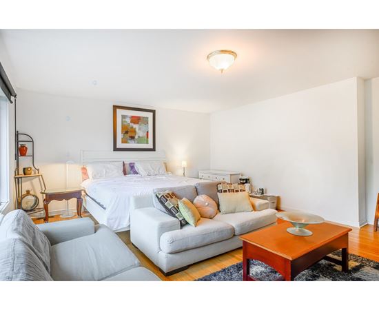 A white bedroom with a large bed and a white couch.