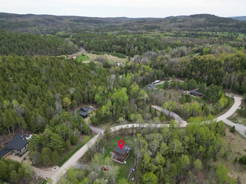 A bird's eye view of a forest with a red house in the center.
