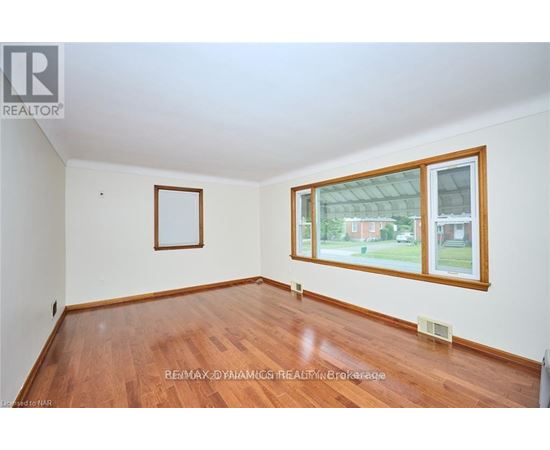 A room with a wooden floor and a window showing a view of a house.