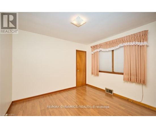 A room with a wooden door and a window with curtains.