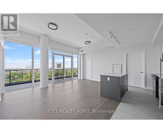A spacious, empty room with a view of the cityscape outside the large windows.