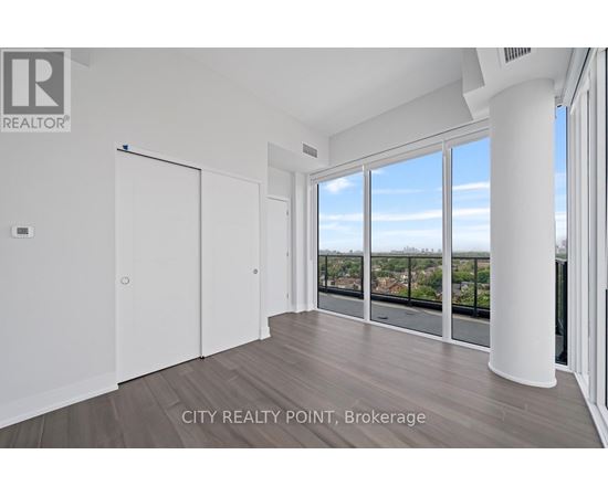A spacious room with a view of the cityscape through large windows.