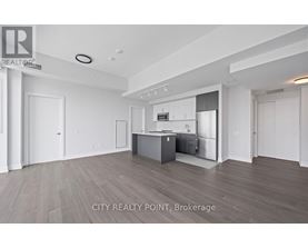 A spacious kitchen with white cabinets and a wooden floor.