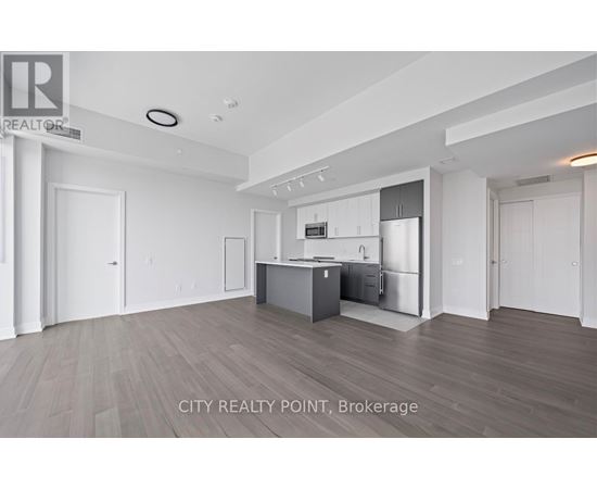 A spacious kitchen with white cabinets and a wooden floor.