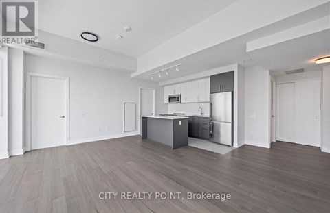 A spacious kitchen with white cabinets and a wooden floor.