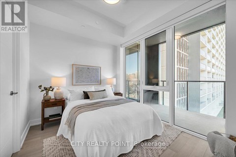 A bedroom with a large bed and a view of a building outside the window.