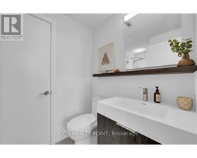 A white bathroom with a toilet, sink, and mirror.