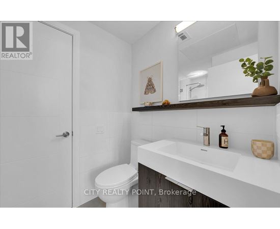A white bathroom with a toilet, sink, and mirror.