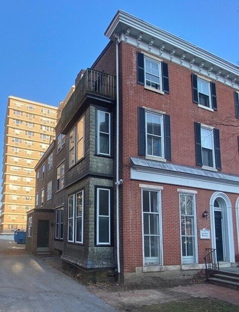 A red brick building with black shutters and a white door.