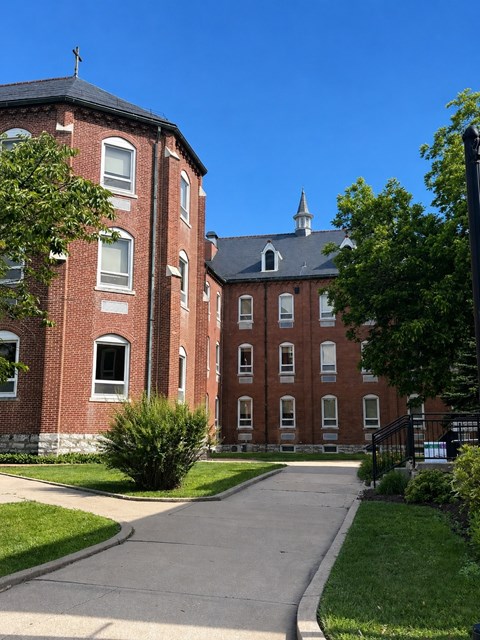A large red brick building with a black roof and a clock tower.
