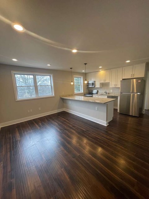 A kitchen with a wooden floor and white cabinets.