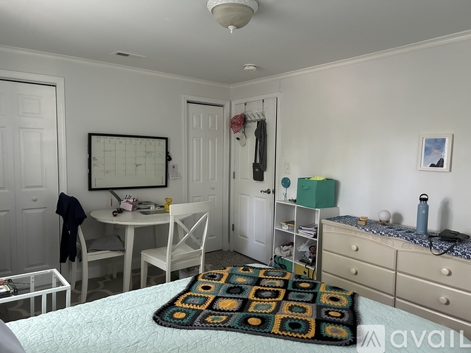 A bedroom with a bed, dresser, and a table with chairs.
