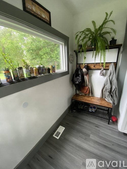 A room with a bench and a window with a view of trees.