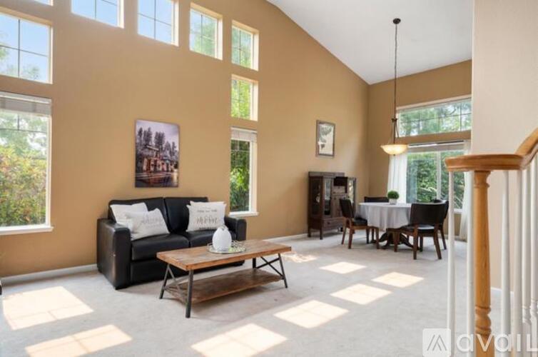 A living room with a black couch, a coffee table, and a dining table set up.