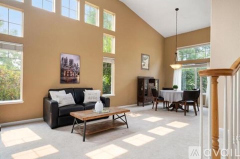 A living room with a black couch, a coffee table, and a dining table set up.
