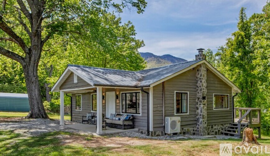 A house with a porch and a tree in front of it.