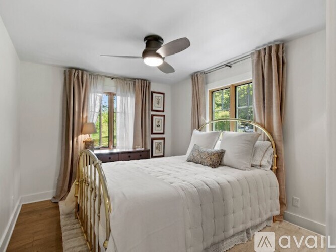 A bedroom with a bed, a ceiling fan, and pictures on the wall.