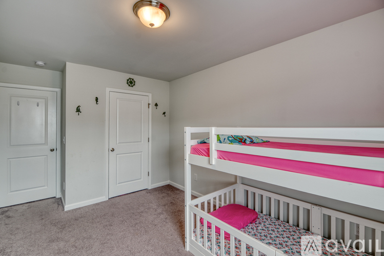 A white bedroom with a bunk bed and two doors.