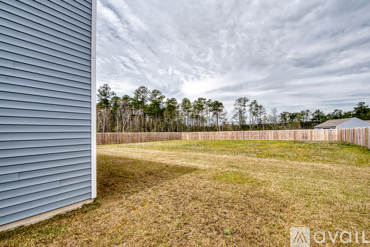 A backyard with a wooden fence and trees in the distance.