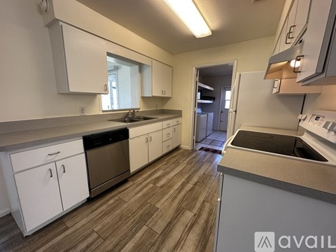 A kitchen with white cabinets and a wooden floor.